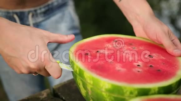 年轻人把刀切成片大的熟红西瓜在大街上阳光明媚视频的预览图
