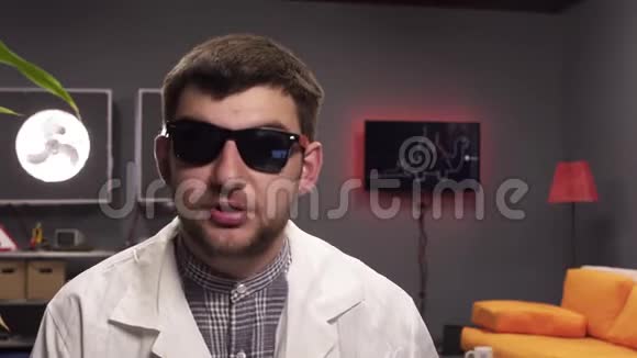 有魅力的家伙带着太阳镜和白色的实验室外套愉快地说话视频的预览图