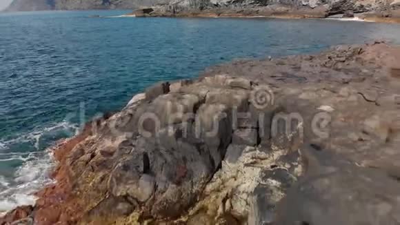 空中射击海岸海洋表面蓝色和绿松石水和火山海岸线的石头和干燥石化熔岩视频的预览图