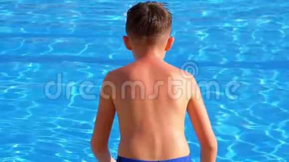 快乐的男孩跳进蓝色的游泳池慢动作视频的预览图
