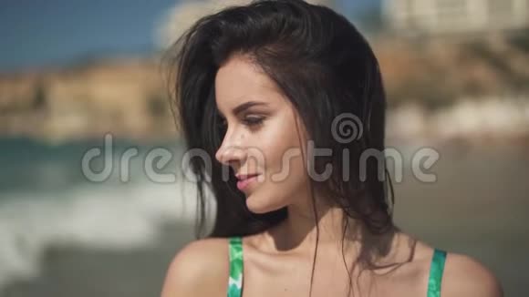 肖像可爱幸福的女孩站在大海的背景上一张漂亮的年轻女人的脸长长的黑发视频的预览图