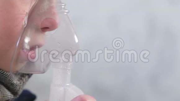 患病男孩通过吸入面罩吸入鼻子和嘴唇特写侧视使用雾化器和吸入器进行治疗视频的预览图