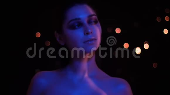 年轻漂亮的白种人女性特写镜头她的妆容是蓝色和红色的霓虹灯背景是bokeh视频的预览图