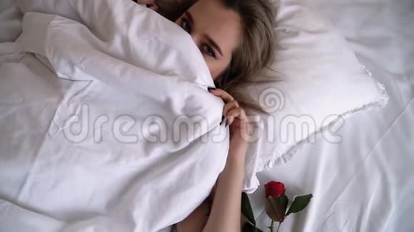 年轻的女士妆容鲜艳鼻子穿孔躺在床上特写女人害羞遮住一半的脸视频的预览图