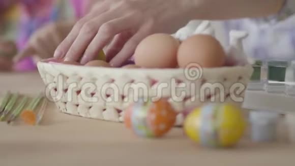 一个女人从篮子里拿出一个鸡蛋的手母女俩在厨房里画复活节彩蛋小型视频的预览图