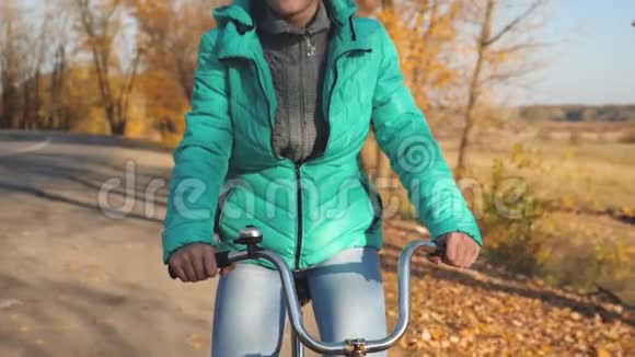 小女孩正在秋天的公园里骑自行车上路女孩的手拿着自行车的弯轮体育运动视频的预览图