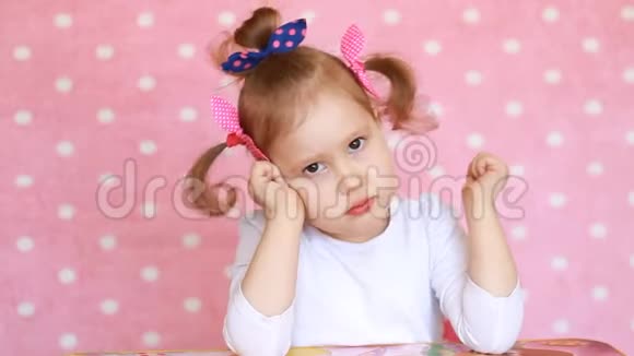 悲伤的女孩看着相机粉红色背景特写上可爱宝宝的肖像视频的预览图