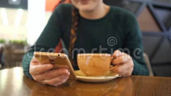 手机在女孩手中的焦点女人正在模糊的背景上喝咖啡视频的预览图