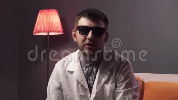 戴着太阳镜和白色实验室外套的白种人男人解释了一些事情视频的预览图