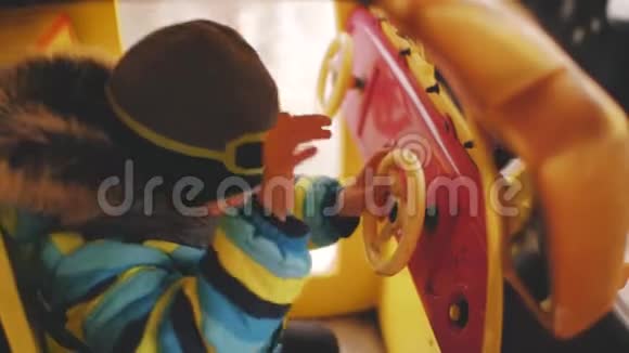 这个男孩戴着头盔帽骑着玩具车在旋转木马上视频的预览图