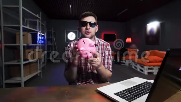 戴着墨镜的滑稽胡子男抱着塑料猪说话看着镜头视频的预览图