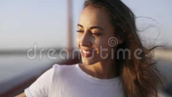 年轻快乐的女人看着傍晚的海上日落美丽的女孩站在桥上欣赏日落美景视频的预览图