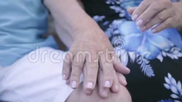 坐在长凳上的成熟男人和女人的特写双手年长夫妇牵着手投标关系视频的预览图