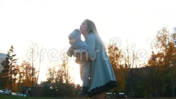 年轻的母亲举起她的小儿子的手把他放在她的肩膀上幸福家庭视频的预览图
