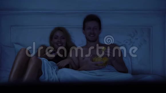 坐在床上看电视吃零食休息的夫妇视频的预览图