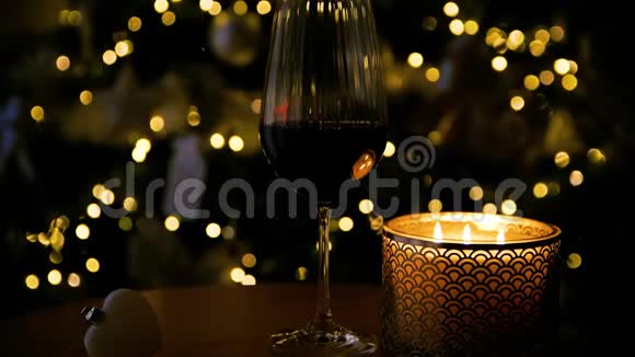 圣诞节的红酒和蜡烛背景中的圣诞树模糊了视频的预览图