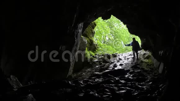 徒步进入洞穴库存录像红色信号蜡烛的旅行者在拱形的背景下进入山坡上的洞穴视频的预览图