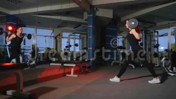 健身房里的女孩向前冲肩膀上戴着杠铃拍打臀部和臀部的肌肉视频的预览图