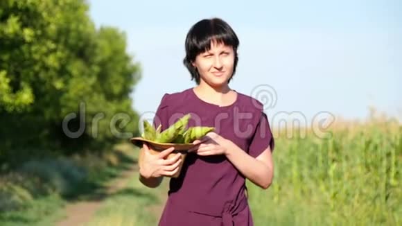 一个年轻的女农民穿过田野手里拿着玉米的收获农业的概念视频的预览图