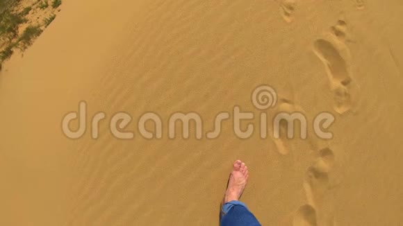 一个人走在沙漠里的沙子上他用手拿着一把沙子把沙子穿过他的手指砂视频的预览图