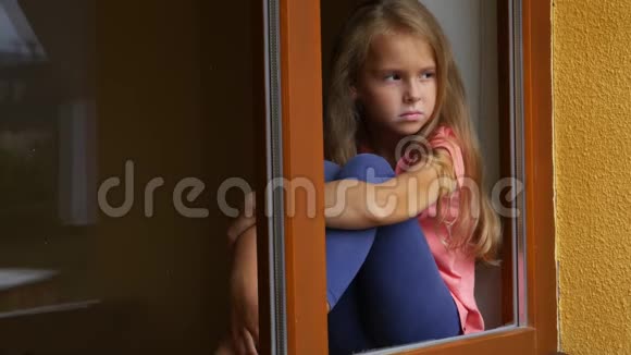 体贴冷漠的女孩望着窗外通过窗口查看视频的预览图