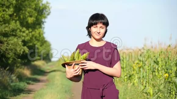 一个年轻的女农民穿过田野手里拿着玉米的收获农业和视频的预览图