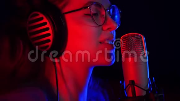 一位戴着眼镜和耳机的年轻女子在录音室录制一首歌视频的预览图