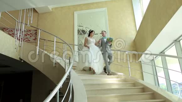 一对新婚夫妇幸福地走下酒店优雅的楼梯视频的预览图