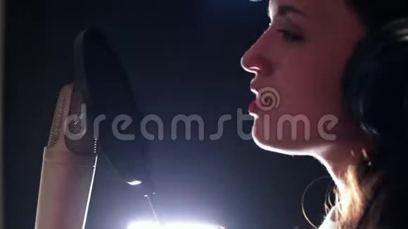 一位年轻迷人的女士在录音室唱歌站在麦克风旁边视频的预览图