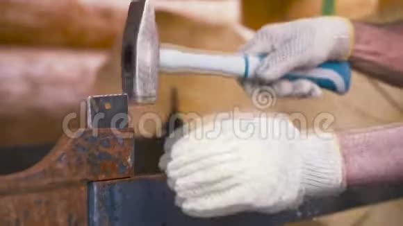 工人戴防护手套在木制原木背景上锤击金属结构剪辑木工工作视频的预览图
