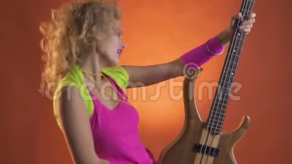 穿着80年代服装的金发女孩用吉他跳舞欣赏音乐视频的预览图