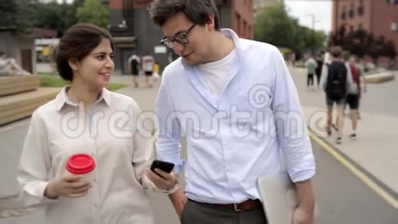 快乐的年轻夫妇走在街上喝着咖啡聊天视频的预览图