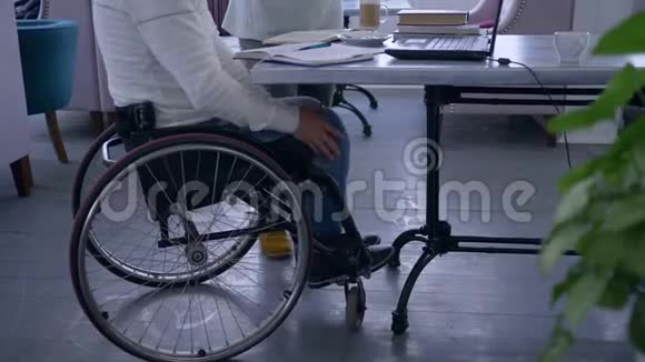 为残疾的成功的坐在轮椅上的老年残疾男子提供辅导让女教育家使用智能计算机技术视频的预览图