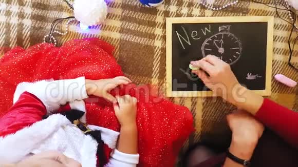 妈妈和女儿在黑板上画新年的属性妈妈和女儿正在画一棵圣诞树新年视频的预览图