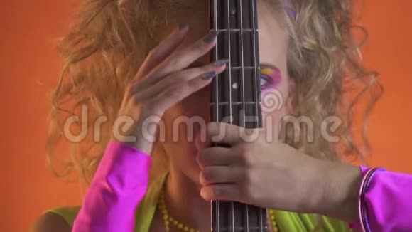 金发女人从吉他后面长着亮妆的眼睛视频的预览图