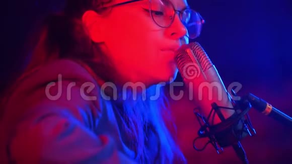一个年轻的女人穿过吉他的弦在霓虹灯中唱着一首歌视频的预览图