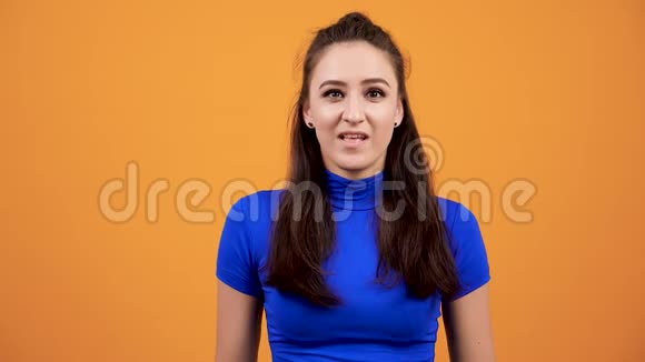 在生动的橙色背景下穿着蓝色t恤的女人在演播室里尖叫视频的预览图
