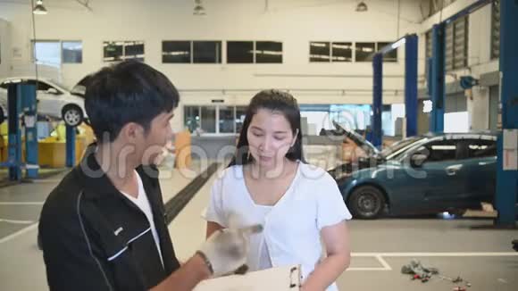 男车技师与客户就汽车修理预算成本和保险进行交谈亚洲女人倾听视频的预览图