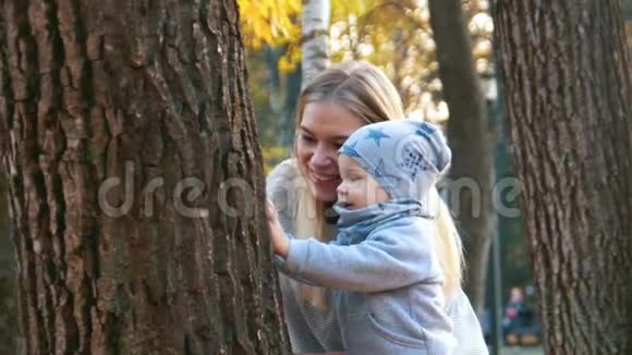 年轻的母亲穿着裙子带着她的小宝宝看树秋天公园视频的预览图