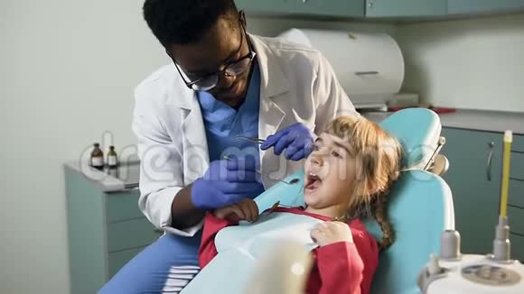 非洲年轻牙医检查小女孩的牙齿视频的预览图