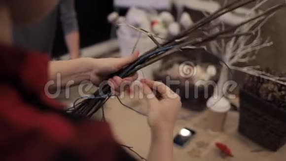 女性双手用蓝色金属丝连接木棒制作花环视频的预览图