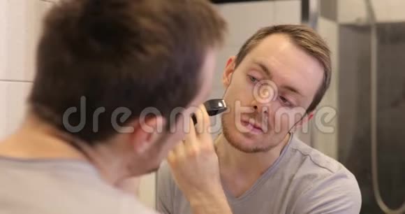 男人刮脸修剪者在浴室里看镜子视频的预览图