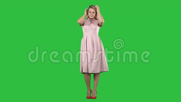 美丽的女士穿着粉红色的连衣裙在绿色的屏幕上铬键视频的预览图