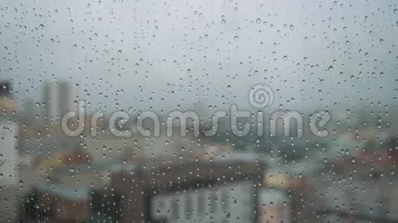 雨滴落在有背景的玻璃上库存录像雨点落在城市背景的窗户上视频的预览图