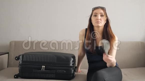 带着手提箱的女孩坐在沙发上挥舞着美元视频的预览图