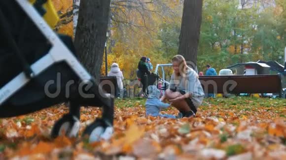 年轻的妈妈穿着裙子和她的小宝宝在秋天公园玩很高的寿命视频的预览图