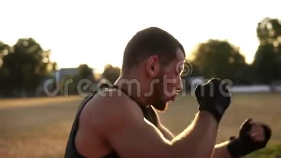 一个穿着黑色绷带的年轻拳击手在户外球场打拳拳击训练太阳照耀着视频的预览图