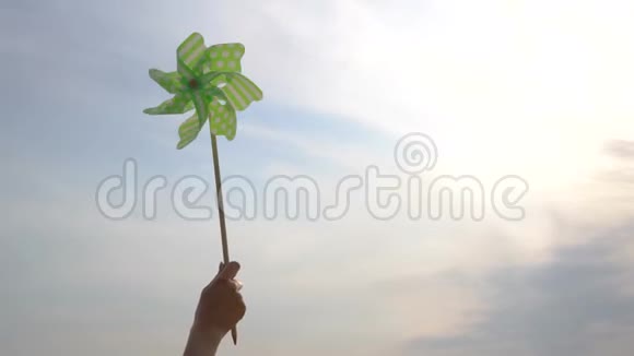 女孩在阳光明媚的天空背景下手握着风车视频的预览图
