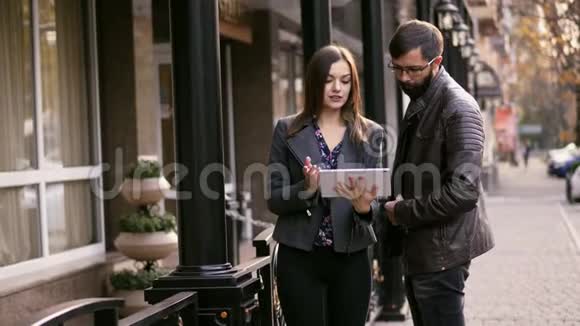 商务男女站着说话在户外使用平板电脑女孩对男人的建议视频的预览图