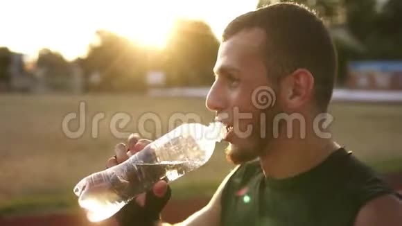 一名身穿黑色绷带的年轻男子拳击手在户外训练期间休息饮用来自视频的预览图